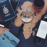 An image of a world map with a passport, magnifying glass, and other travel materials on top of it.