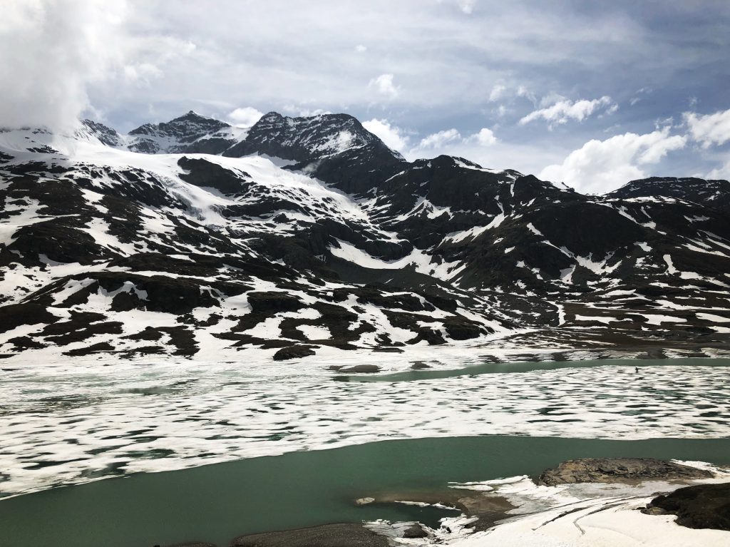 photo of a frozen lake and snow covered mountains