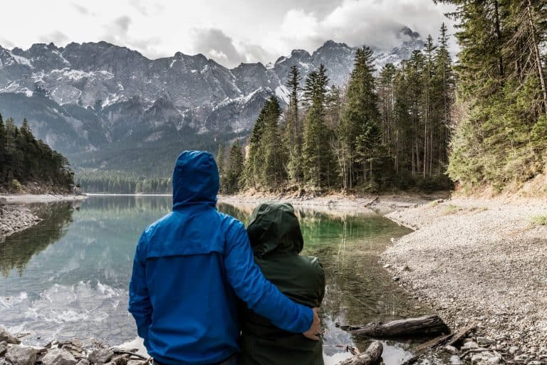 featured photo for this post - a photo of a couple standing in front of a lake with mountains in the background