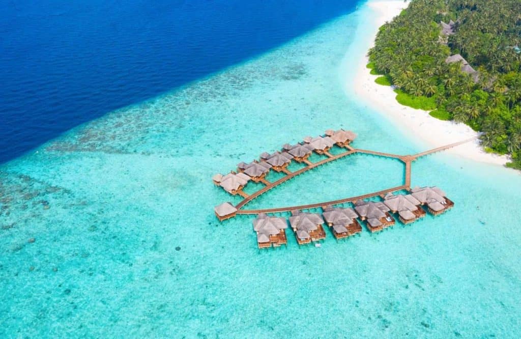 Two rows of overwater bungalows over the crystal clear blue seas on the Maldives.