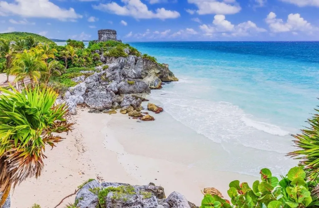 Green palm trees and ancient ruins along the pristine shores of Tulum packing list.