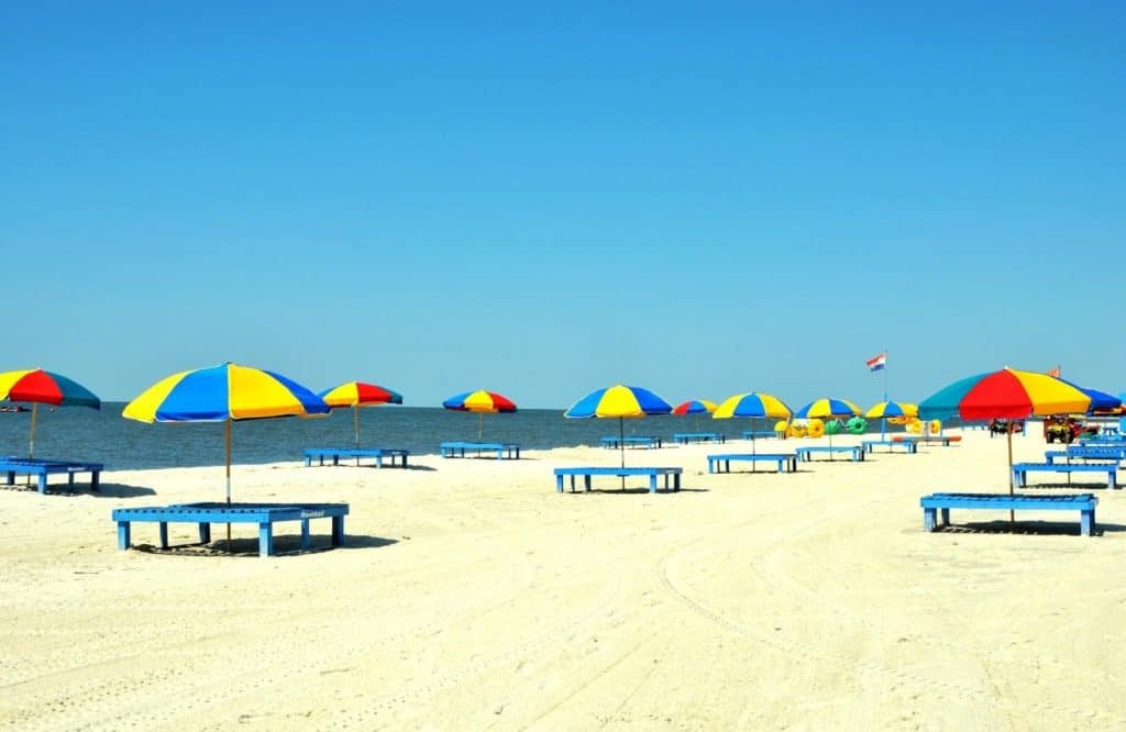Umbrellas and chairs lined up along Biloxi Beach so that visitors can enjoy the beachy things to do in Biloxi.