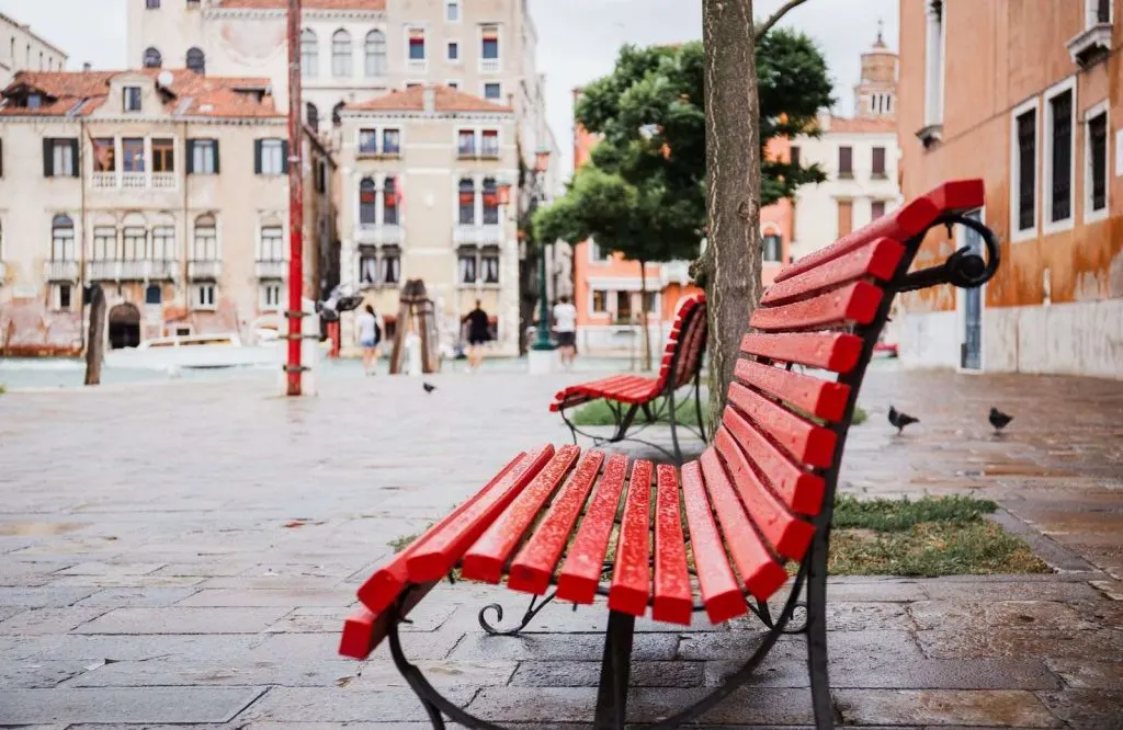 A red bench in a square, and one of the most important things to know before going to Venice is that it's a pedestrian friendly city.