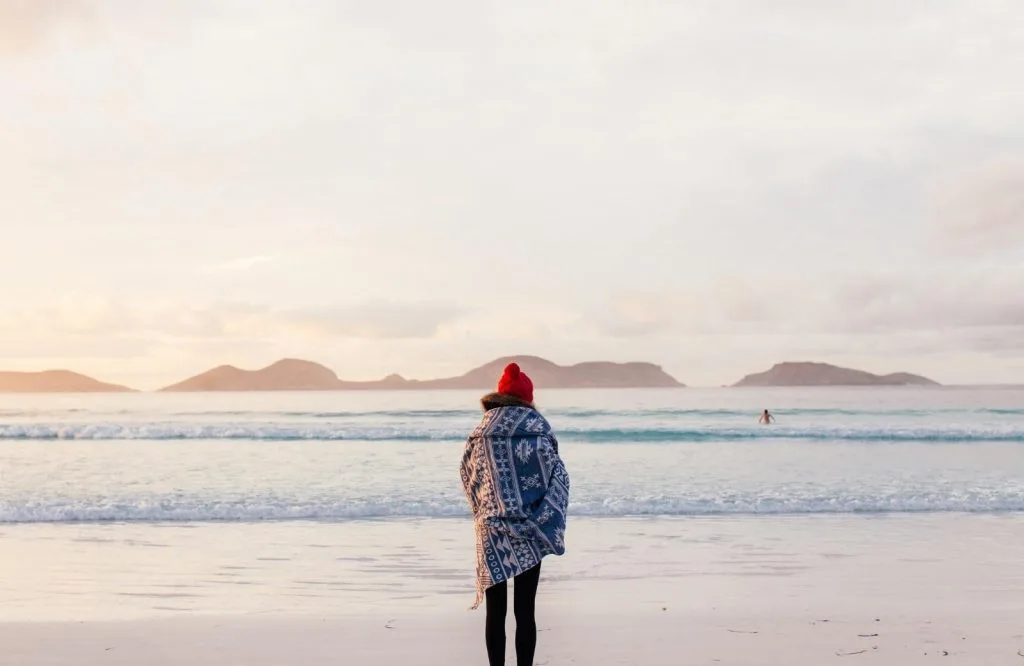 A female solo traveler standing on the ocean for traveling alone quotes.