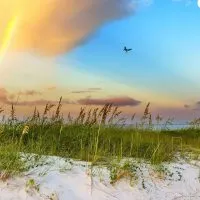 Rainbow on the beach with grass growing in the sand depicting Biloxi, Mississippi