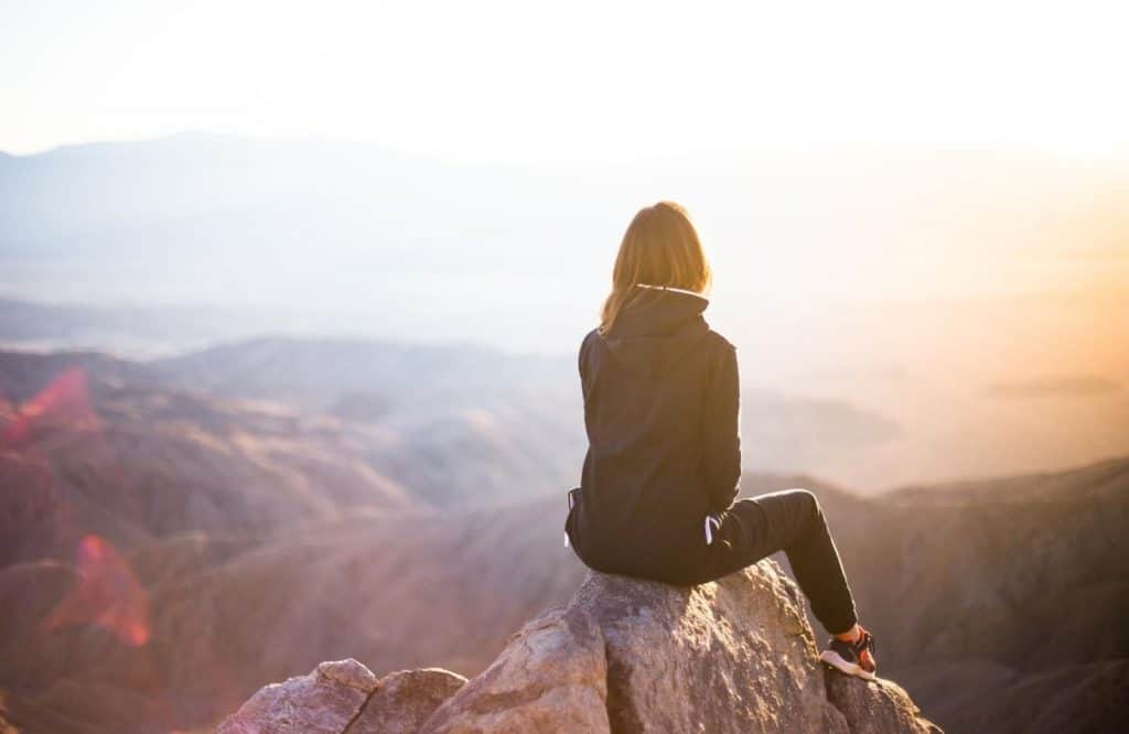A woman sitting on a mountain for traveling alone quotes.