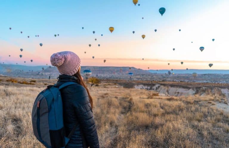 A solo female traveler looking at hot air balloons for traveling alone quotes.