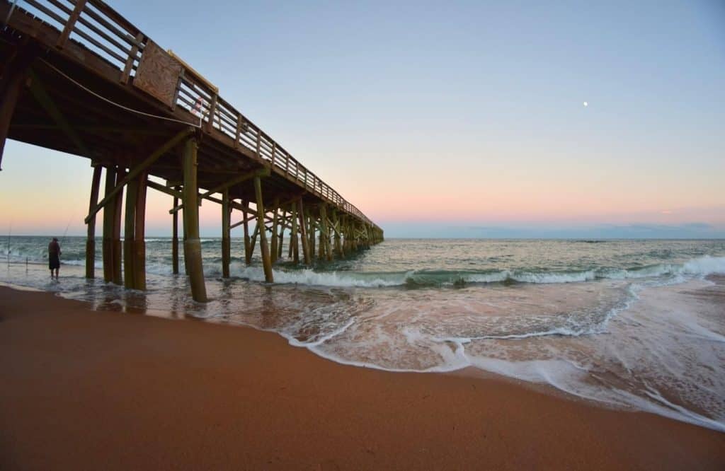 A man fishing under the pier at Flagler Beach which is one of several small beach towns in Florida.