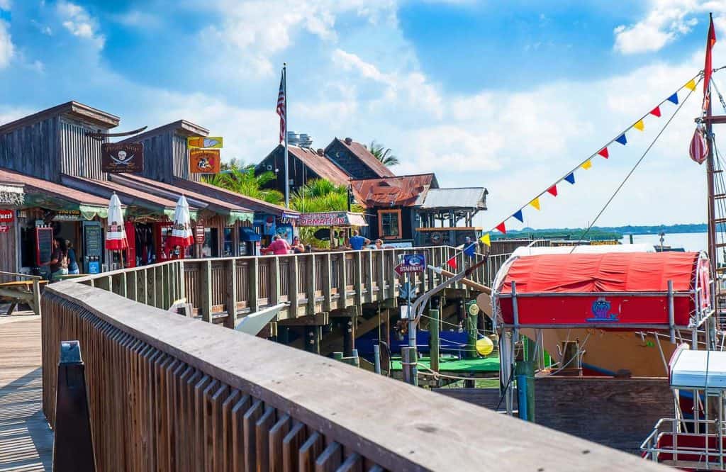 A boardwalk and pier lined with restaurants and shops on Madeira Beach which is one of the best small beach towns in Florida.