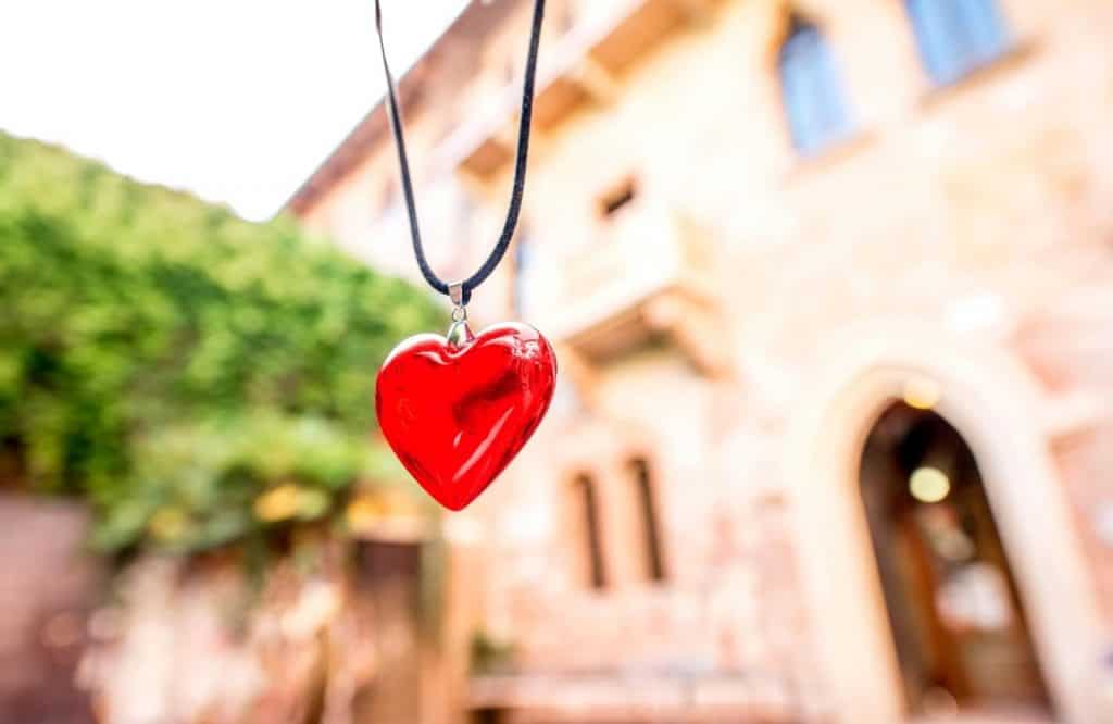 A red heart in front of a building symbolizing Romeo and Juliet which is what is Italy famous for.