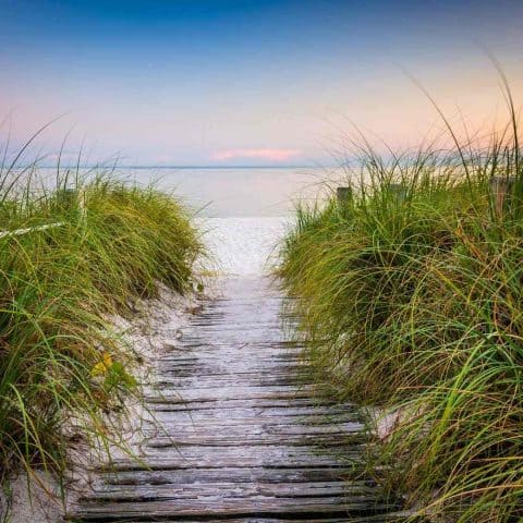 A boardwalk leading to the beach during sunset showing one of the best small beach towns in Florida.