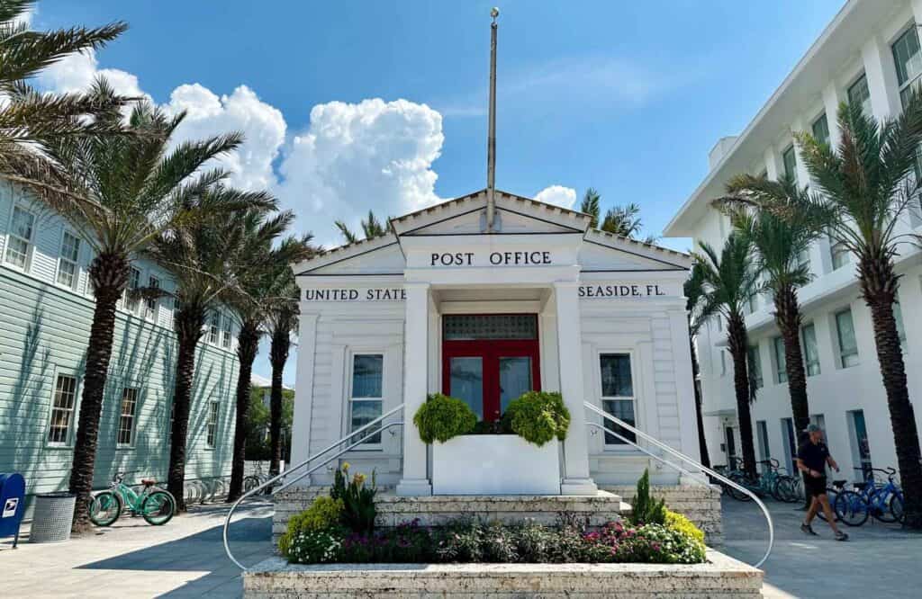 A white colored post office in Seaside, Florida surrounded by palm trees on both sides of it.