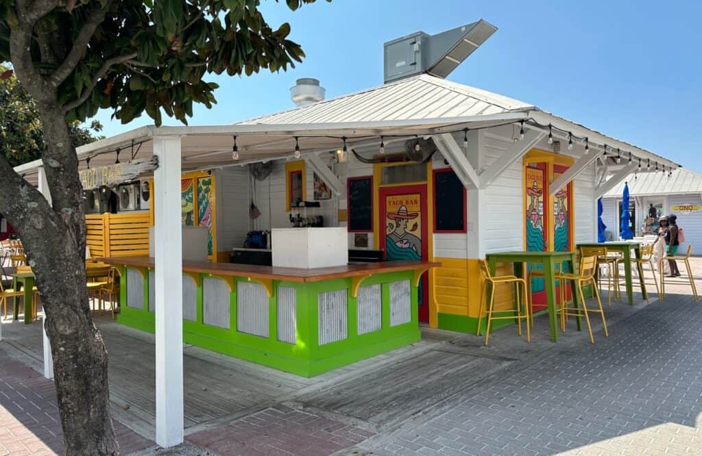 A white, green, and yellow taco bar restaurant that looks like a beach shack in Seaside Florida.