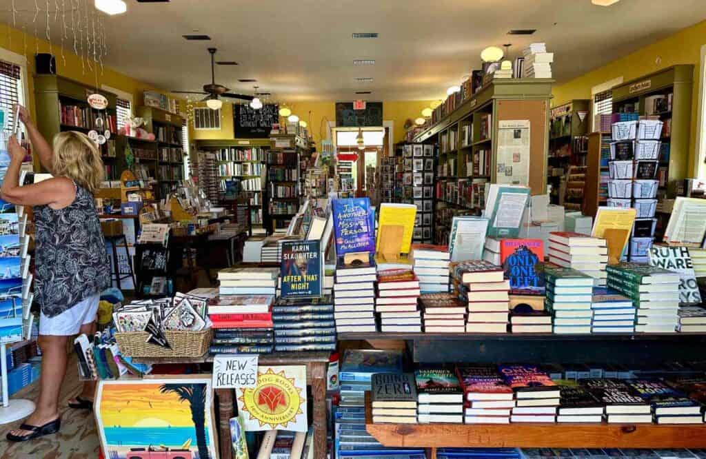 The inside of Sundog Books with tables covered with books and a woman searching for a book.