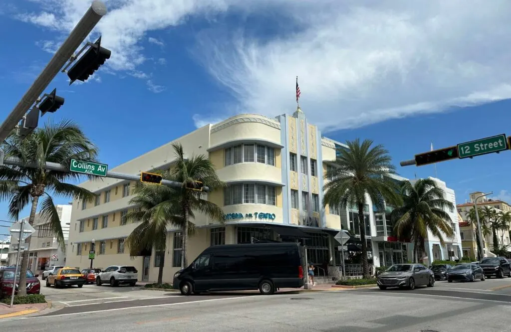 An intersection with an art deco style cream colored building at the corner in the Art Deco Historic District during a day in Miami.
