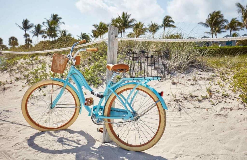 Bicycle on the sand with palm trees in the background.
