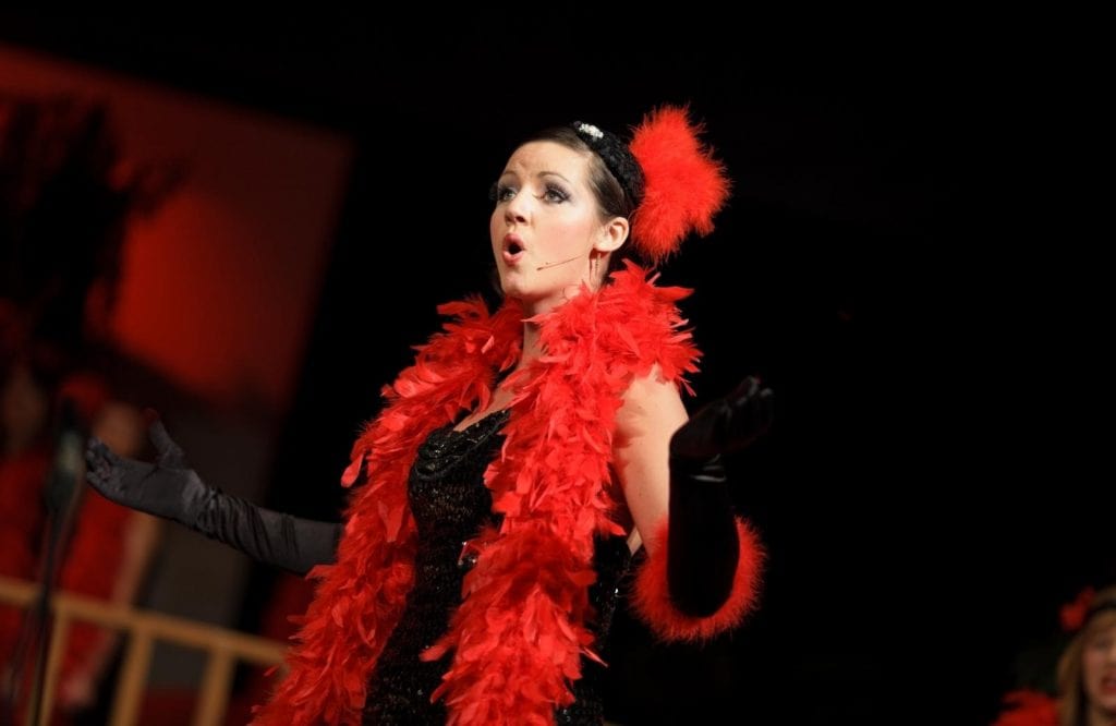 A woman dressed in red performing at a music theatre.