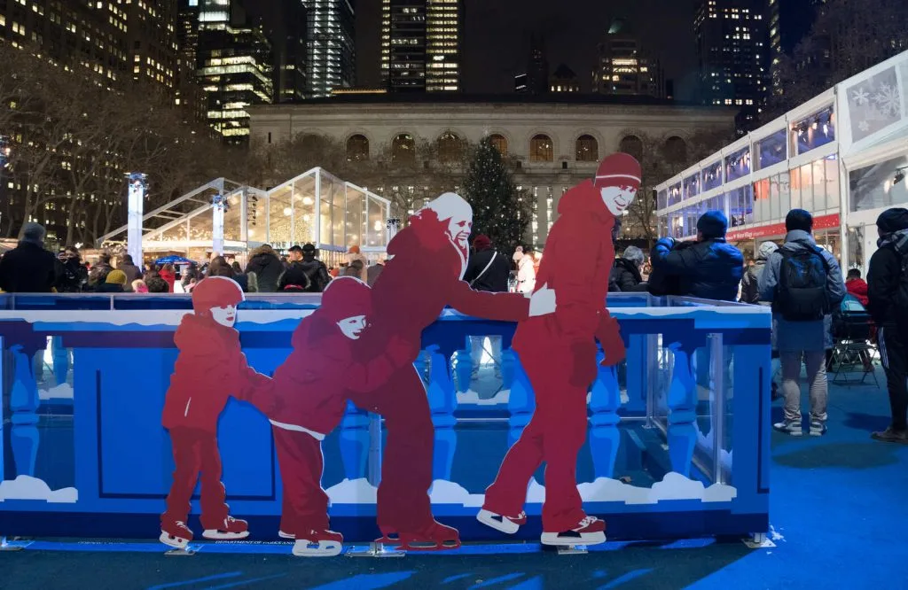 Red cutout statues of people ice skating at Bryant Park Winter Village.