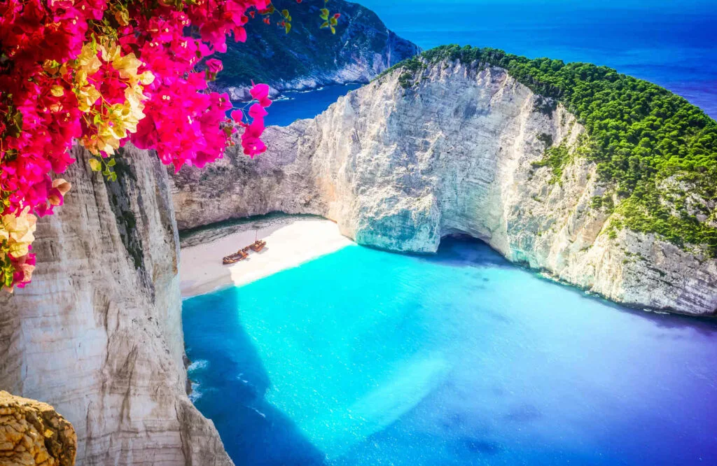 Aerial view of Navagio Beach in Zakynthos with cliffs and a gorgeous bright blue beach.