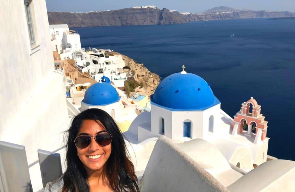 Me standing in front of the blue domed churches in Santorini during one of my Greek island holidays for couples.