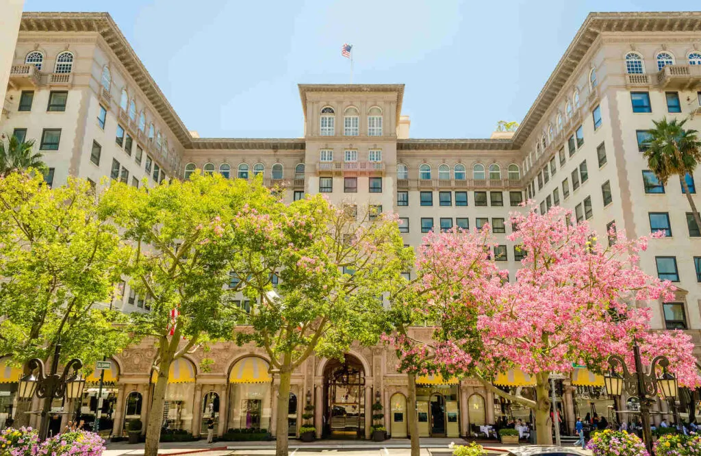 The Beverly Wilshire, A Four Seasons Hotel in Beverly Hills with a pink blossoming tree in front of it.