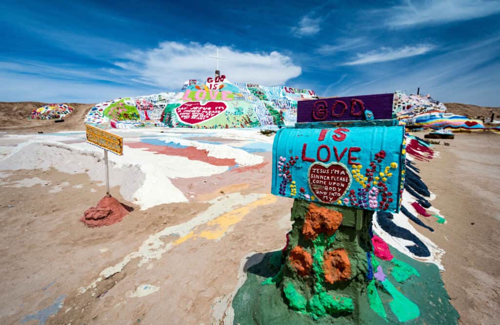 A colorful mountain with graffiti type decorations and lettering on Salvation Mountain in Salton Sea.