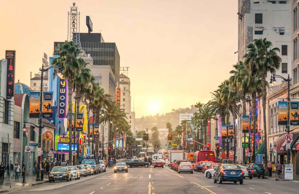 Sunset Strip and Hollywood street view with bars and shops on both sides with the sun setting in the background.