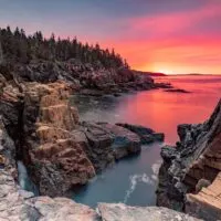 Cliffs and trees along the ocean at sunset, which is one of the best places to visit in Maine.