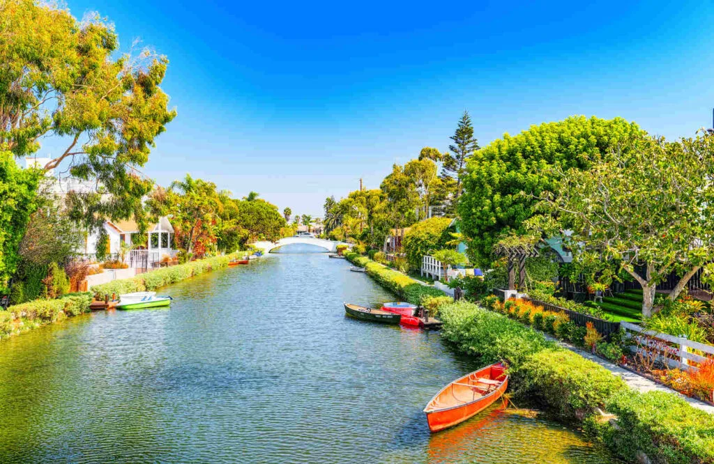 Canal lined with houses and small canoes which are the Venice Canals in Venice, California.