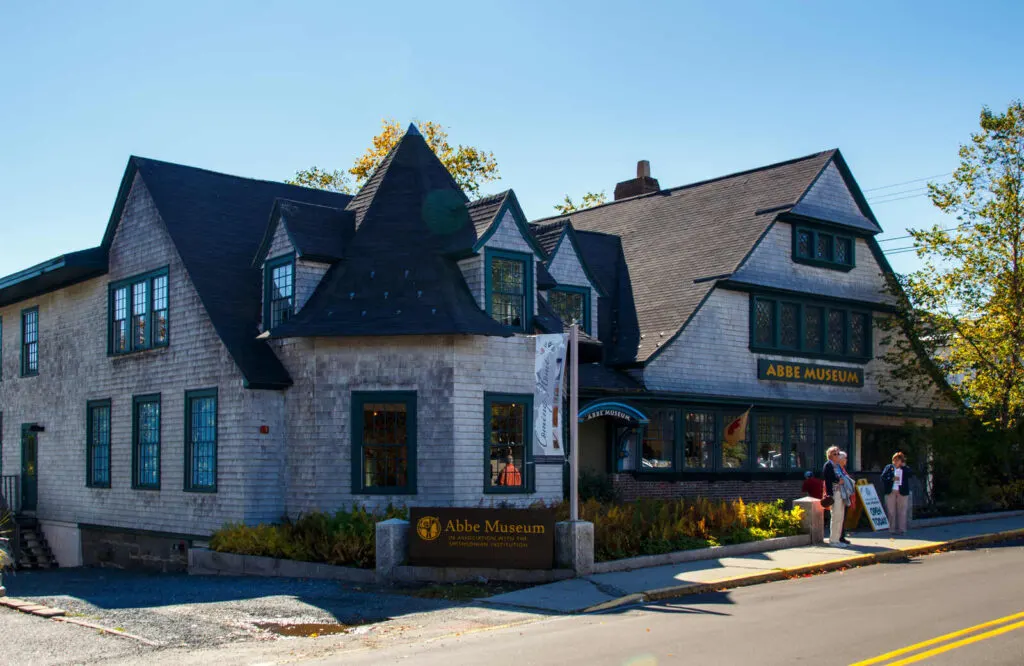 The exterior of the Abbe Museum in Bar Harbor with people standing outside of it.