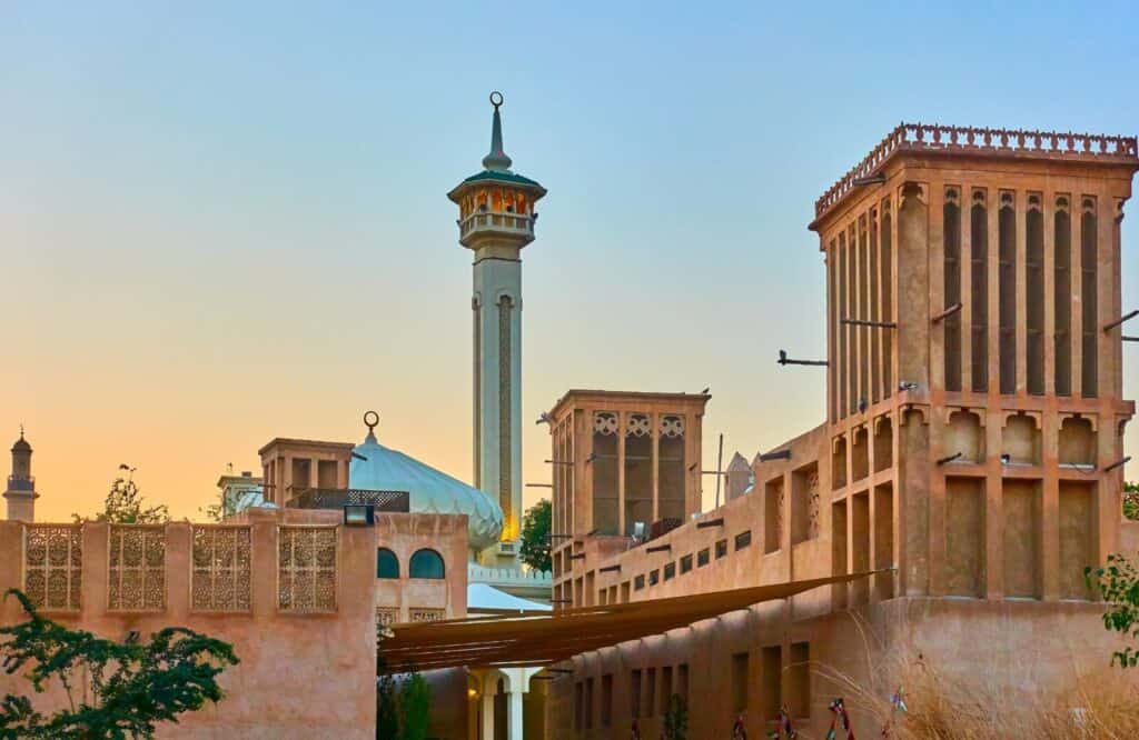 Al Fahidi Historical Neighbourhood with historical buildings and a tall tower at sunrise or sunset.