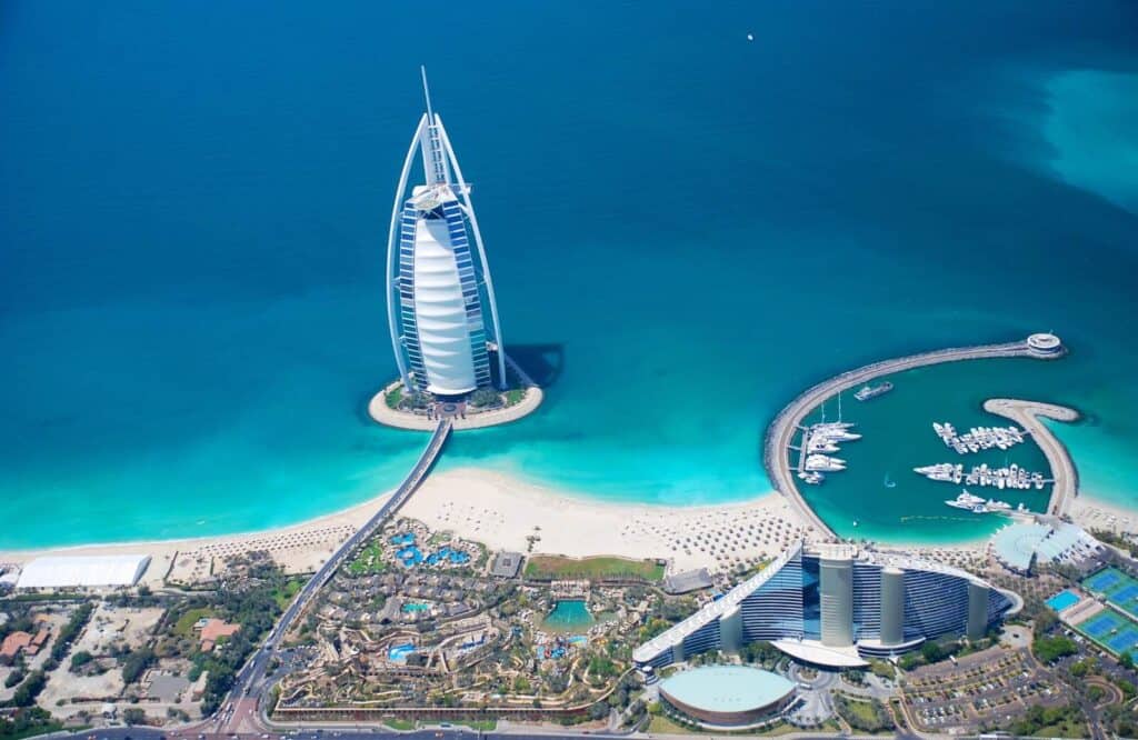 Aerial view of the Burj Al Arab in Dubai and it's set on the ocean with bright blue waters.