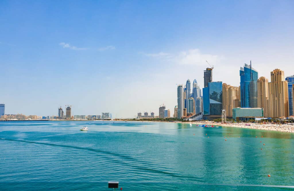 Aerial view of Jumeirah Beach in Dubai with blue waters and skyscrapers lining the sand.