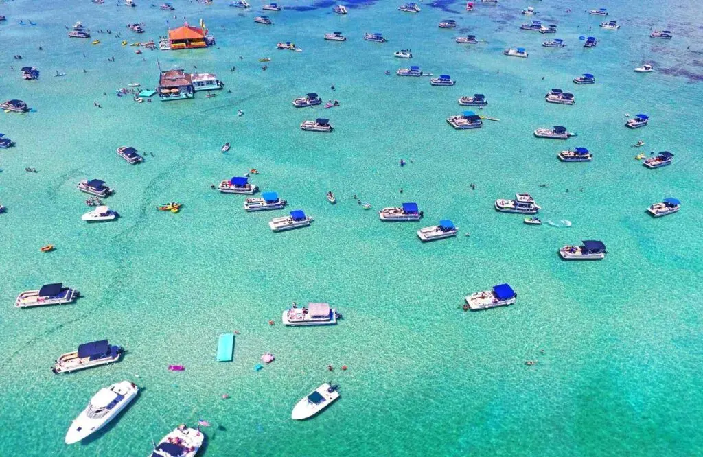 Aerial view of Crab Island, one of the best beaches in Destin Florida, with several boats on the clear turquoise waters.