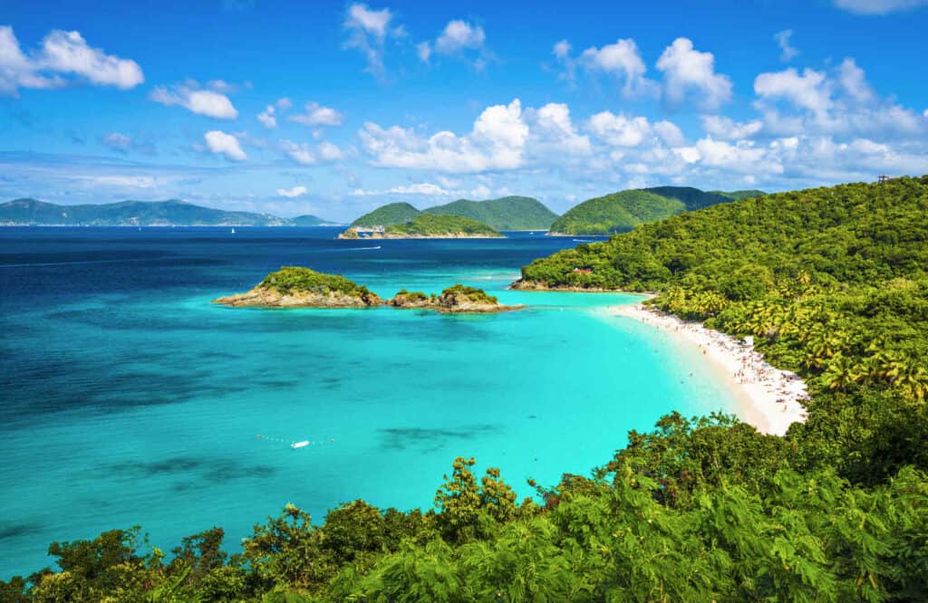 Overlook of Trunk Bay in St. John in the Virgin Islands National Park in the background with crystal clear blue waters and lush trees.