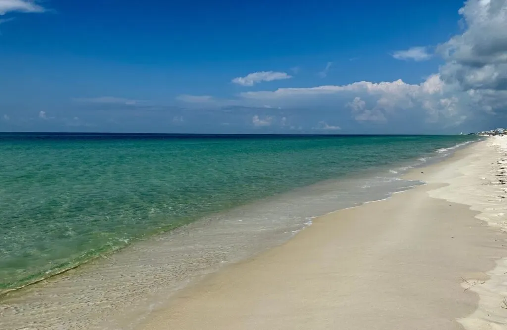 White and powdery sand along the shore with blue and emerald clear waters at Camp Helen State Park in Florida.