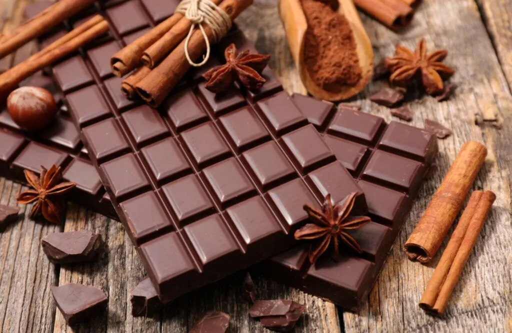 Chocolate bars with cinnamon sticks and anise cloves scattered around them for decorative purposes.