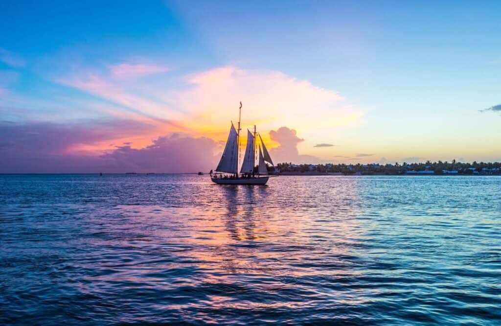 Sunset with light purple, yellow, and orange skies with a sailing boat in Key West.