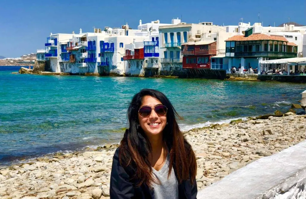 A woman sitting on a bench in front of Little Venice in Mykonos, Greece.