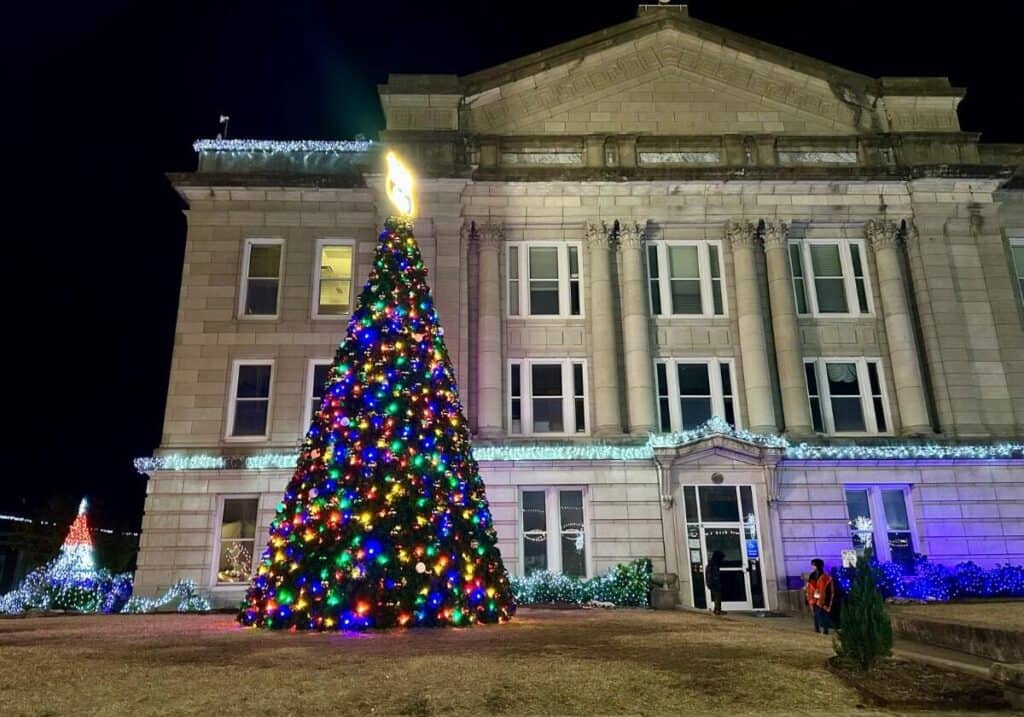 A giant Christmas tree with colorful lights and a Route 66 tree topper in front of the Creek County Courhouse.