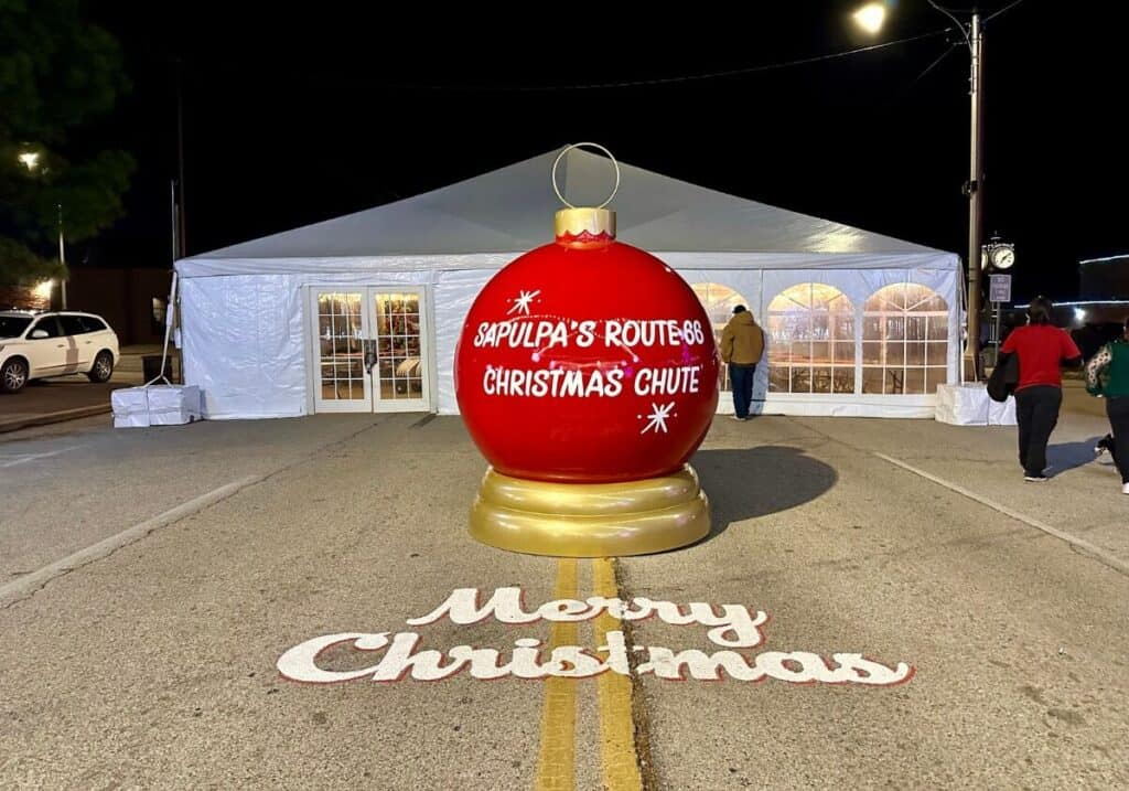 A giant red ornament in front of a white tent that says 