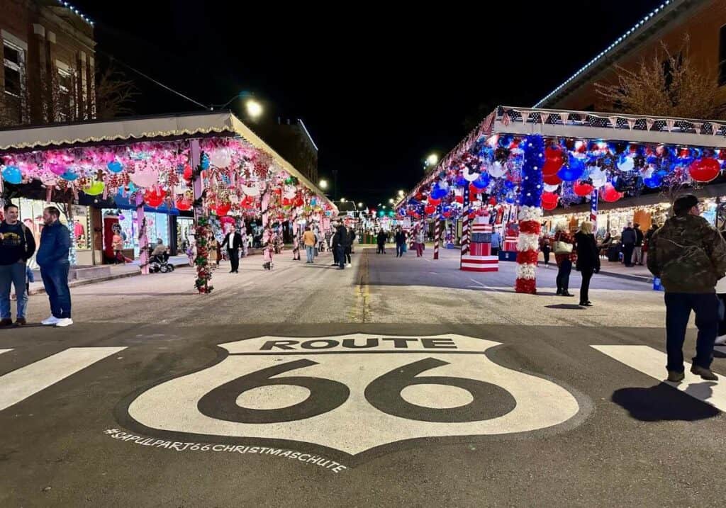 A giant Route 66 sign painted on the road with large colorful Christmas decorations on each side of the road at the Route 66 Christmas Chute in Sapulpa, Oklahoma.