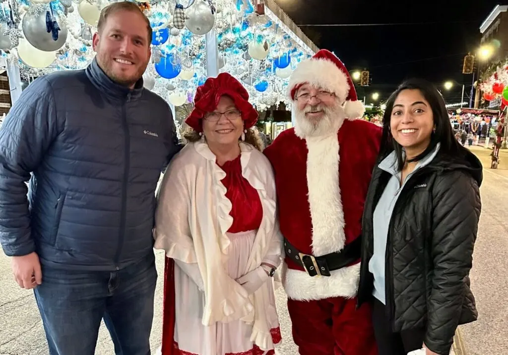 A man and woman posing with Mrs. Claus and Santa Claus at the Route 66 Christmas Chute.